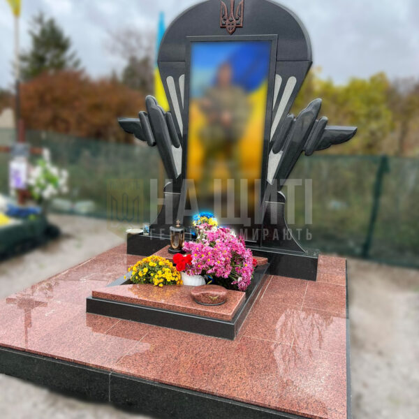 Військовий пам'ятник з червоного граніту з тризубом і зображенням героя в арці