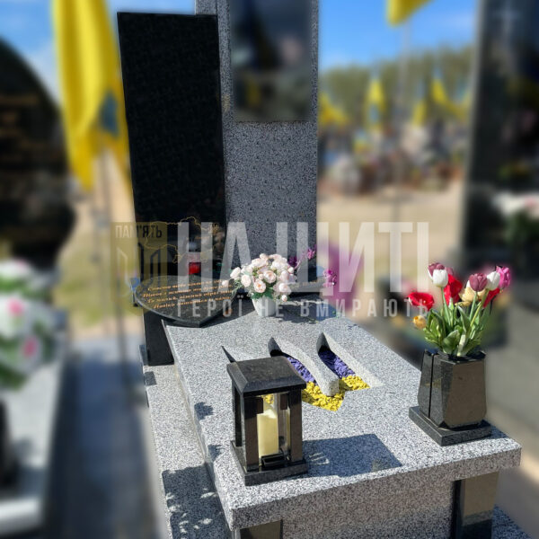 Пам'ятник для воїна з сірого і чорного граніту з хрестом та лампадкою пам'яті.
