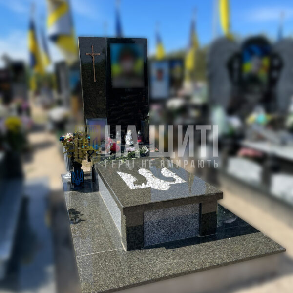 Темний гранітний пам'ятник для військового з гербом України та білим хрестом.